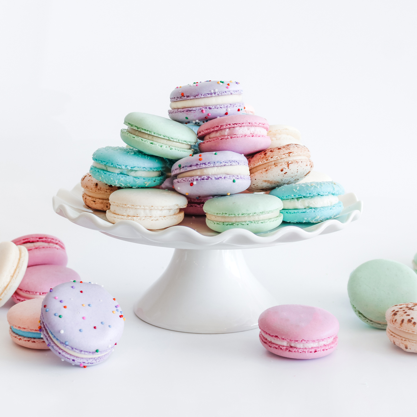 A white platter with pastel coloured macarons stacked on top of it